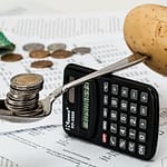 budgeting, money, potato, and spoon balanced on a calculator