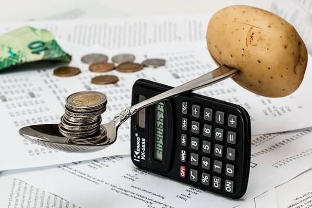 budgeting, money, potato, and spoon balanced on a calculator